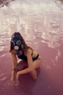Female in swimwear and mask crouched in dirty pool with litter — Stock Photo