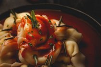 Ravioli cotti con salsa di pomodoro ed erbe aromatiche in ciotola accanto a forchetta e tovagliolo sul tavolo — Foto stock