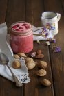 Frullato di lamponi in vaso di vetro con latte di mandorla servito su tavolo rustico con tovagliolo — Foto stock