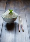 Schüssel mit traditionellem japanischen Reis und Stäbchen auf Holztisch. — Stockfoto