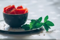 Corte pedaços de melancia na tigela decorados com folhas de hortelã e milho na toalha de mesa — Fotografia de Stock