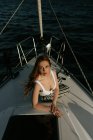 Apelante y atractiva mujer pelirroja mirando a la cámara mientras viaja en barco - foto de stock