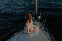 Розслаблена красива жінка сидить на носі корабля і відпочиває, насолоджуючись морською подорожжю із закритими очима — стокове фото