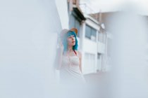 Relaxed woman with blue hair in hat and sundress strolling along city street at summer day — Stock Photo