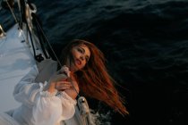 Ruhige Frau in luxuriösem weißen Kleid, die während einer Kreuzfahrt auf einer Jacht liegt und wegschaut — Stockfoto