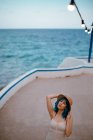Inspirierte Frau mit blauen Haaren, Hut und Sonnenbrille schlendert am Betonsteg am bunten Meer entlang — Stockfoto