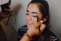 Atraente jovem mulher recebendo maquiagem por profissional cosmética trabalhador no salão — Fotografia de Stock