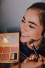 Bela jovem mulher ficando reforma por profissional maquiagem artista no salão — Fotografia de Stock