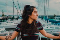 Felice giovane tatuato donna in abito in piedi sul molo pieno di yacht e barche — Foto stock