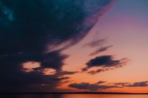 Impresionante y colorida puesta de sol en las cálidas noches de verano, reflejando ligeramente en la superficie marina. - foto de stock