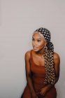 Mulher americana africana adulta bonita no lenço de cabeça estampado marrom do vestido e brincos olhando afastado no fundo cinzento — Fotografia de Stock