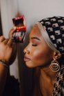Черная взрослая женщина накладывает тень от профессионального визажиста в студии — стоковое фото