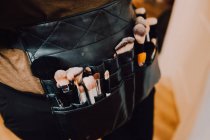 Makeup artist wearing apron bag with various brushes for work — Stock Photo