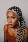 Beautiful adult African American woman in brown dress patterned headscarf and earrings looking away on grey background — Stock Photo