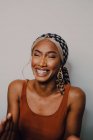 Mulher americana africana adulta bonita no lenço de cabeça estampado marrom do vestido e brincos olhando afastado no fundo cinzento — Fotografia de Stock