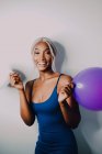Joyful Black adult woman with colorful balloons looking at camera while standing on white background — Stock Photo