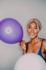 Joyeuse Noire adulte avec des ballons colorés regardant la caméra sur fond blanc — Photo de stock