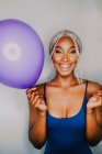 Joyful Black adult woman with colorful balloons looking at camera while standing on white background. - foto de stock