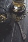 From above of dried daisy in spoon on dark wooden table near cup with herbal tea — Stock Photo
