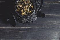 Getrocknetes Gänseblümchen zum Teekochen in Metall-Teekanne auf dunklem Tisch — Stockfoto
