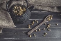Montón de margaritas secas en cuchara de madera sobre mesa oscura para hacer té - foto de stock