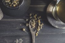De cima da margarida secada na colher na mesa de madeira escura perto da xícara com o chá herbal — Fotografia de Stock