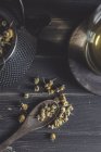 Зверху сухої ромашки в ложці на темному дерев'яному столі біля чашки з трав'яним чаєм — стокове фото