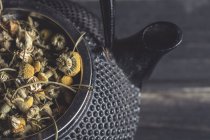 Closeup of dried daisy heap for tea making in metal teapot on dark table — Stock Photo