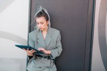 Donna d'affari con acconciatura alla moda e vestito utilizzando laptop a parete — Foto stock