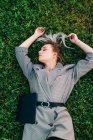 Vista superior da mulher de negócios na moda descansando, levantando as mãos e deitado na grama verde com laptop — Fotografia de Stock