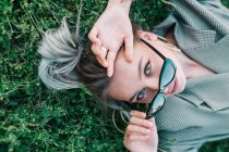 Модна бізнес-леді відпочиває з сонцезахисними окулярами на зеленій траві — стокове фото