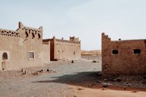Das Äußere schäbiger traditioneller arabischer Gebäude mit Ornamenten auf der Straße einer Kleinstadt vor wolkenlosem Himmel in Marokko — Stockfoto