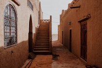 Exterior de antigas casas árabes tradicionais com escadaria e janelas ornamentais na rua estreita da cidade em Marrocos — Fotografia de Stock