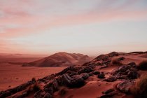 Céu nublado sobre colinas e rochas no deserto árido à noite em Marrocos — Fotografia de Stock