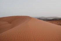 Collina dalla sabbia asciutta in mezzo al grande deserto contro il cielo grigio in Marocco — Foto stock