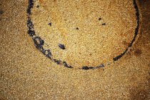 Closeup of sandy surface with round imprint and dark drops — Stock Photo