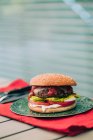 Deliciosa hamburguesa casera de ternera con lechuga, tomate y salsa en plato verde . - foto de stock