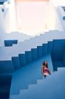 Vista lateral da mulher andando no andar de cima no edifício azul moderno e olhando para cima — Fotografia de Stock