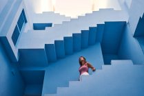Vista lateral da mulher andando lá em baixo no moderno edifício azul — Fotografia de Stock