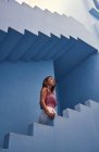 Vista lateral da mulher andando no andar de cima no edifício azul moderno e olhando para cima — Fotografia de Stock