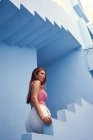 Vista lateral da mulher andando no andar de cima no edifício azul moderno e olhando para longe — Fotografia de Stock
