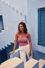 Jovem mulher de pé no moderno edifício azul e olhando para longe — Fotografia de Stock