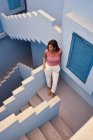 Vista superior da jovem mulher andando no andar de cima no edifício azul moderno e olhando para longe — Fotografia de Stock