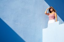 Жінка стоїть на вершині синьої будівлі і дивиться в сторону — стокове фото