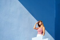 Donna in piedi sulla cima di un edificio blu e guardando altrove — Foto stock