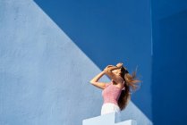 Frau steht auf blauem Gebäude und lehnt sich kopfüber zurück — Stockfoto