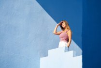 Frau steht auf blauem Gebäude und schaut weg — Stockfoto