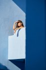 Donna in piedi sulla cima di un edificio blu e guardando altrove — Foto stock