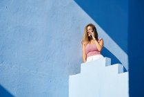Femme debout sur le dessus du bâtiment bleu et parler par smartphone — Photo de stock