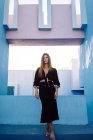 Frau steht auf modernem blauen Gebäude und schaut weg — Stockfoto